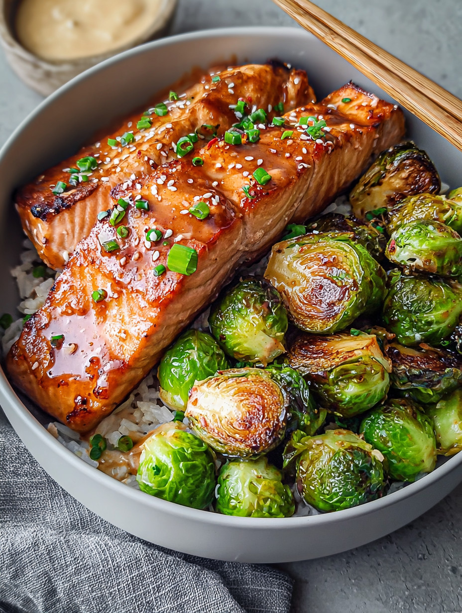 A bowl of food with salmon and brussels sprouts.