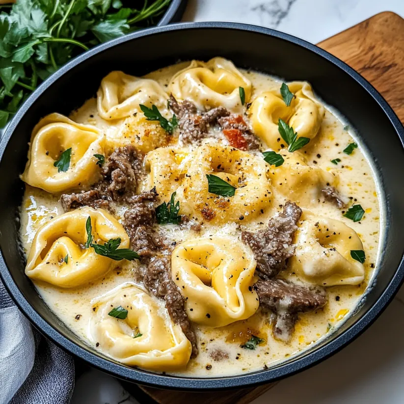 A bowl of cheesesteak tortellini in creamy provolone sauce.