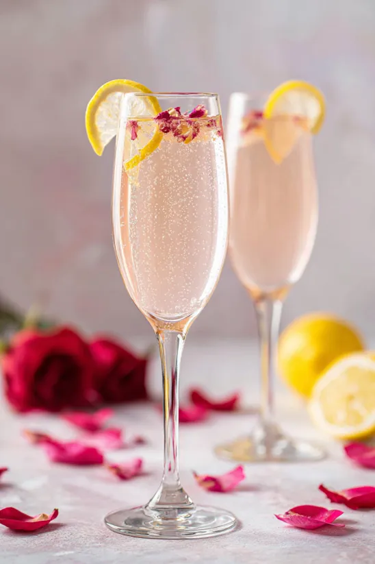 Two glasses of pink lemonade with lemon slices and rose petals.