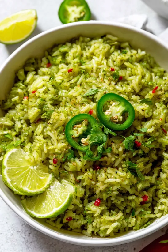 A bowl of rice with green peppers and lime.