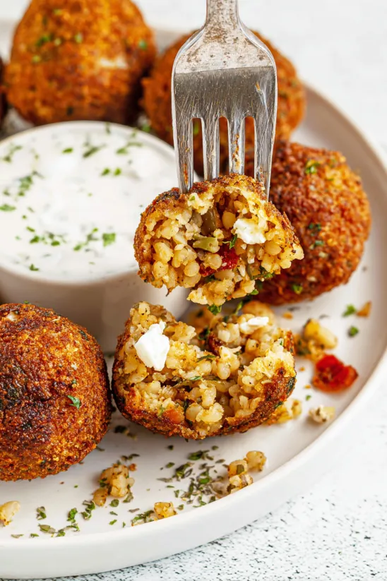 A plate of boudin balls with a fork in the middle.