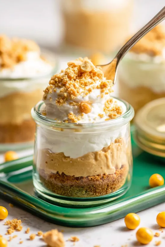 A small dessert in a glass jar with a spoon in it.