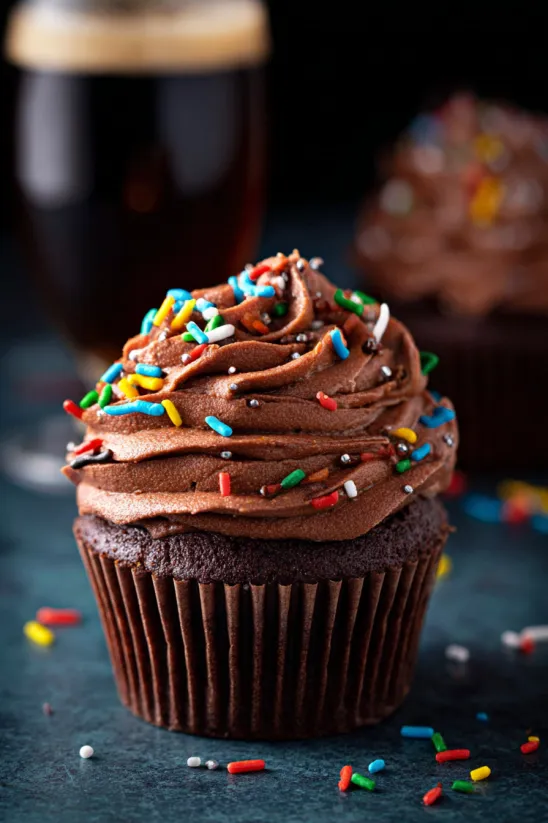 A chocolate cupcake with sprinkles on top.