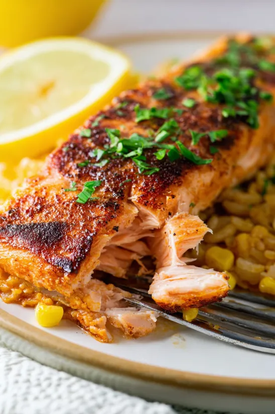 A piece of cooked salmon with rice and lemon.