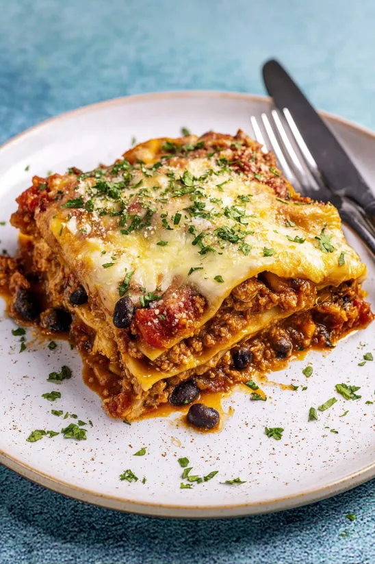 A plate of Mexican lasagna with a fork on the side.