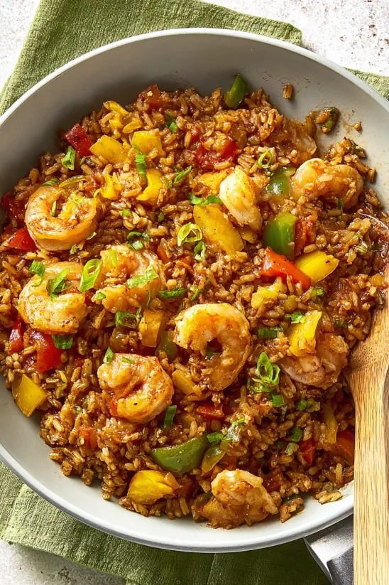 A bowl of rice with shrimp and pineapple.