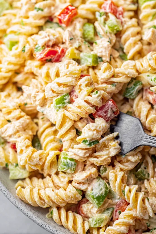 A fork is stuck in a bowl of tuna pasta salad.