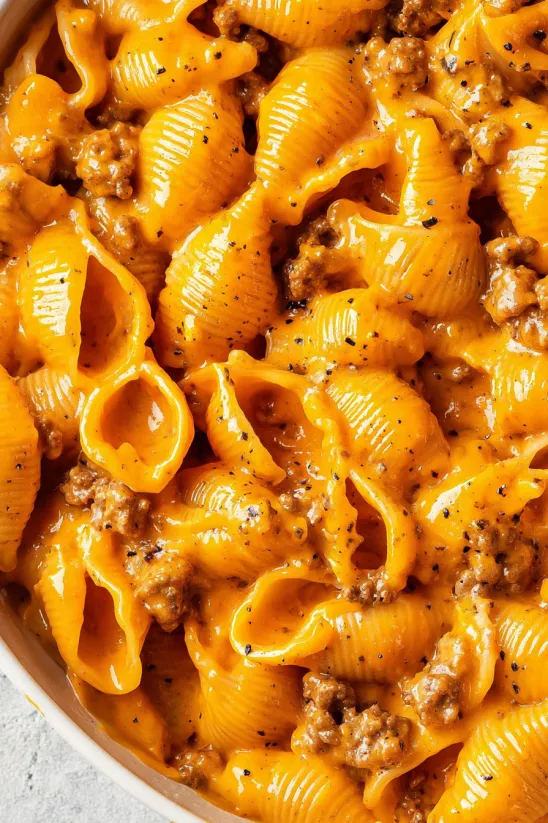 A bowl of macaroni and cheese with meat on top.