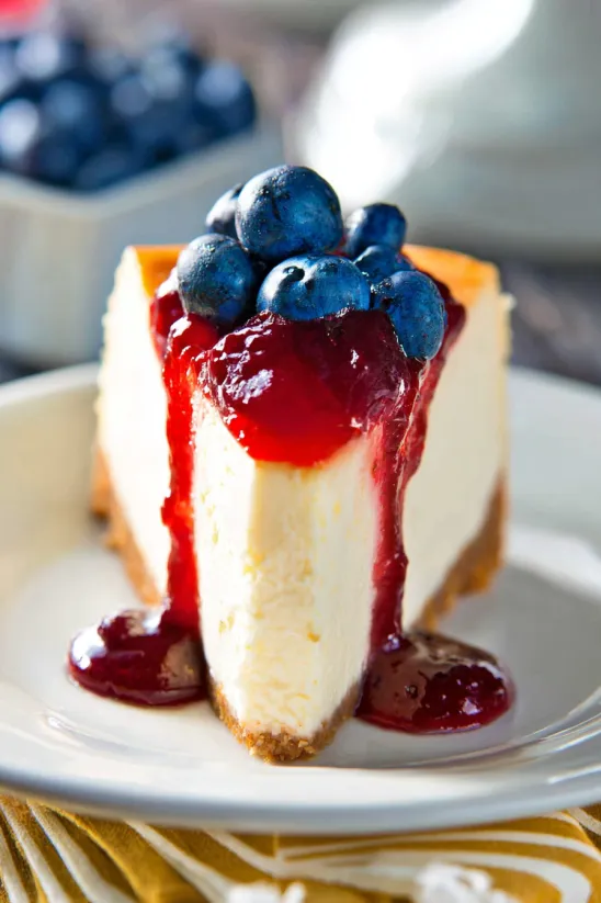 A slice of cheesecake with blueberries on top.