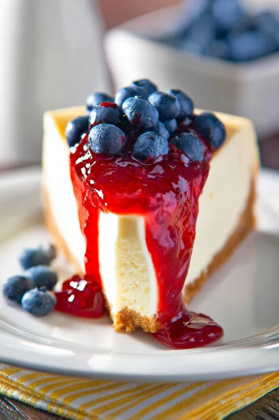 A slice of cheesecake with blueberries on top.