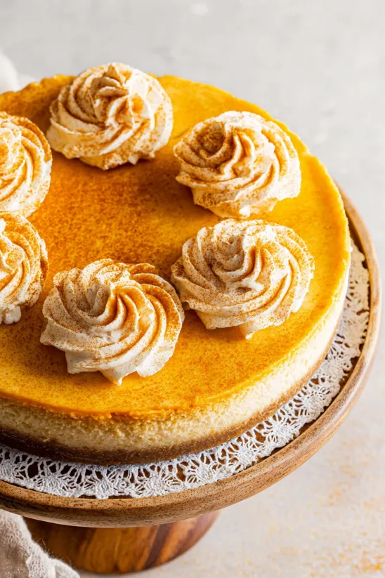 A slice of pumpkin cheesecake with brown and white toppings.