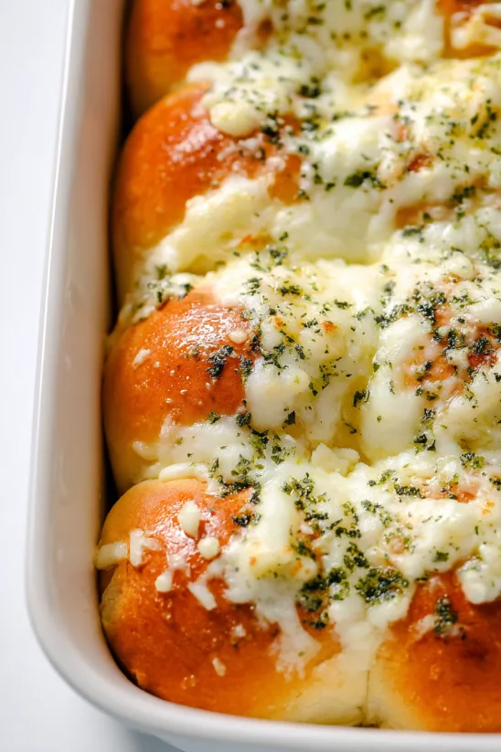 A white bowl filled with cheesy garlic Hawaiian rolls.