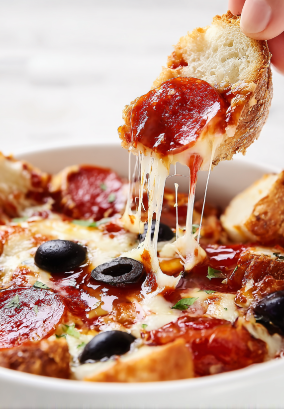 A slice of pizza is being dipped into a bowl of sauce.