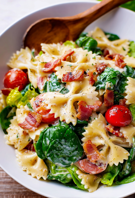 A bowl of pasta salad with bacon and tomatoes.