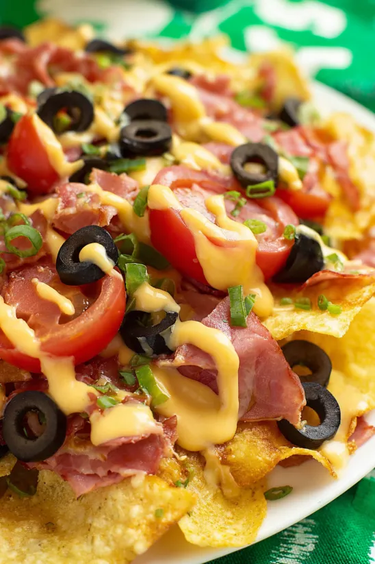 A plate of Irish nachos with meat, tomatoes, and olives.