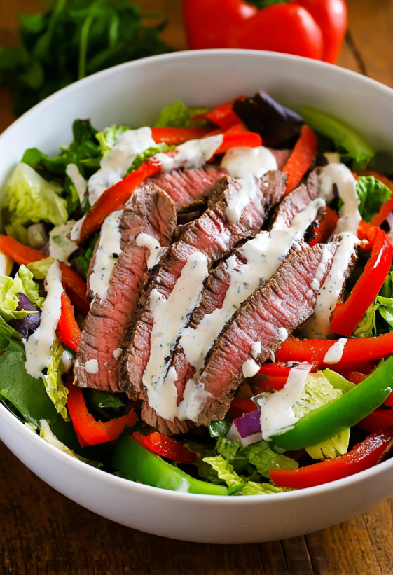 A bowl of steak fajita salad with chipotle ranch dressing.