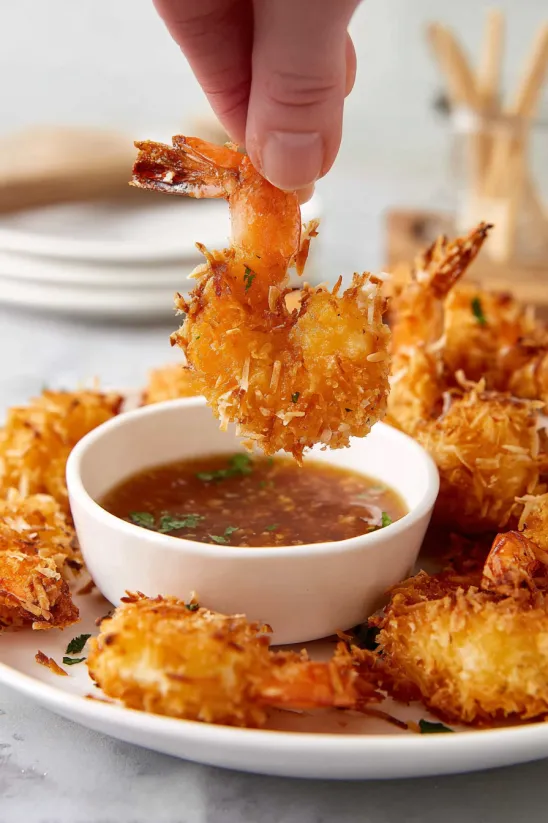 A person is holding a piece of coconut shrimp.