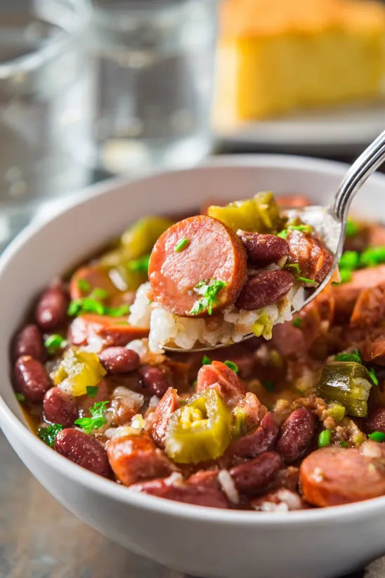 A spoon is in a bowl of red beans and rice.
