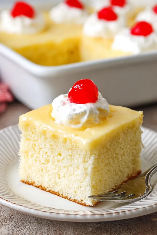 A slice of tres leches cake with whipped cream on top.