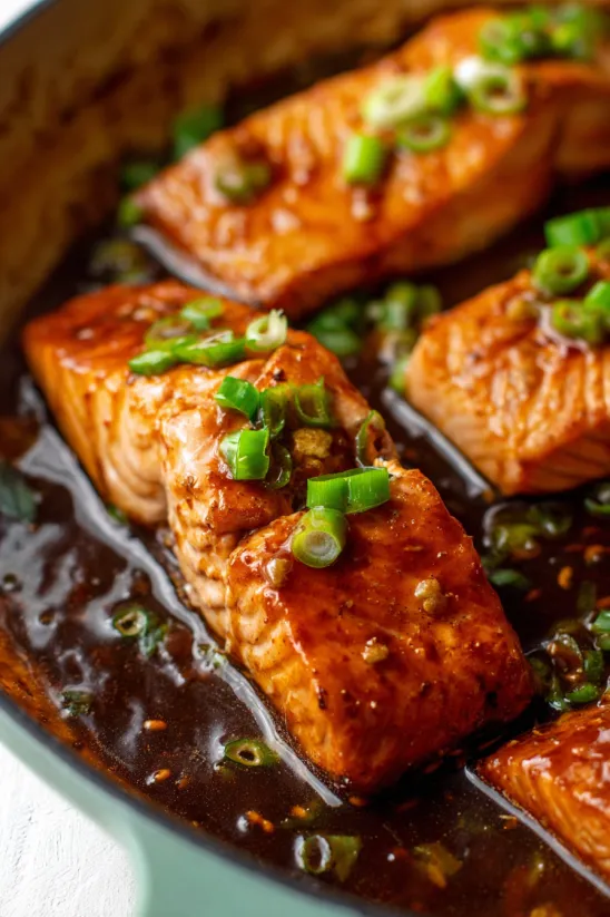 A dish of teriyaki salmon with green onions.