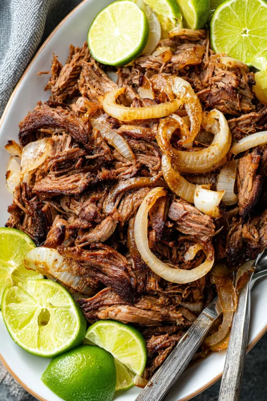 A plate of beef with onions and limes.