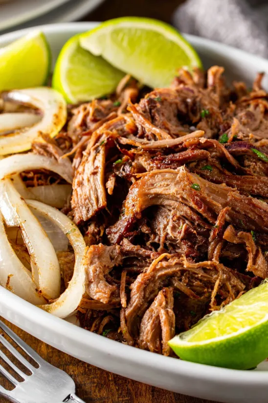 A plate of beef with onions and limes.