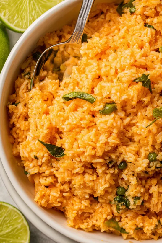 A bowl of rice with green peppers and lime.