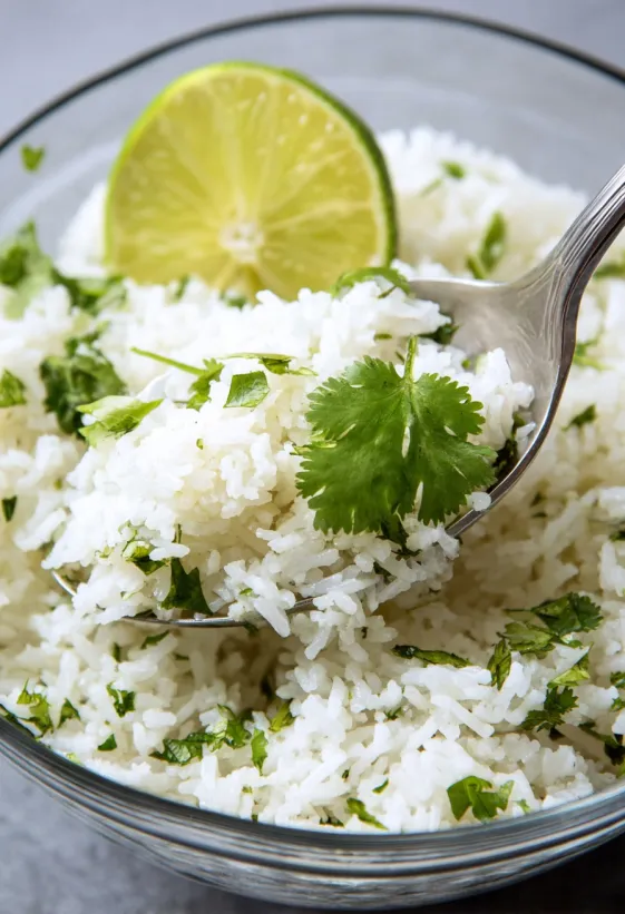 A bowl of rice with cilantro and lime.