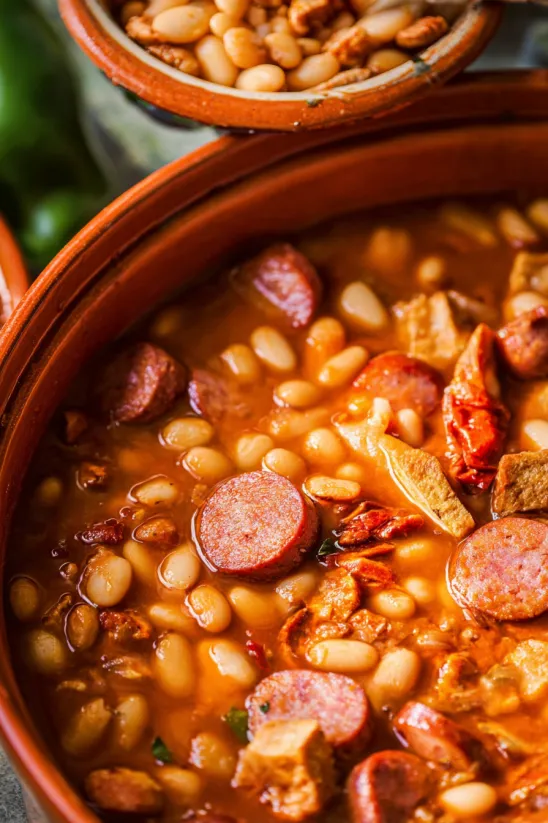 A bowl of beans with a sausage in it.