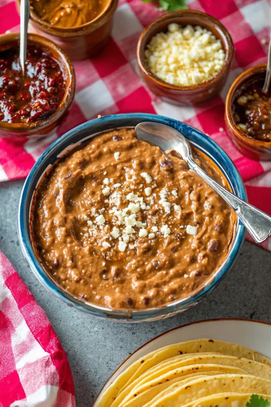 A bowl of refried beans with a spoon in it.