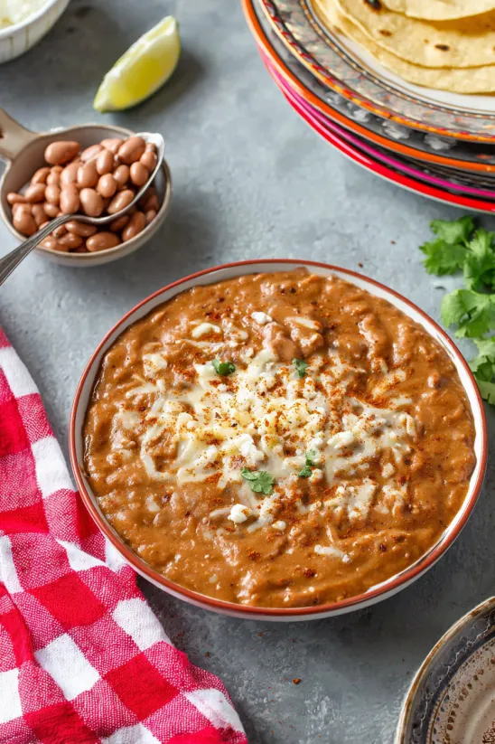 A bowl of refried beans with cheese on top.