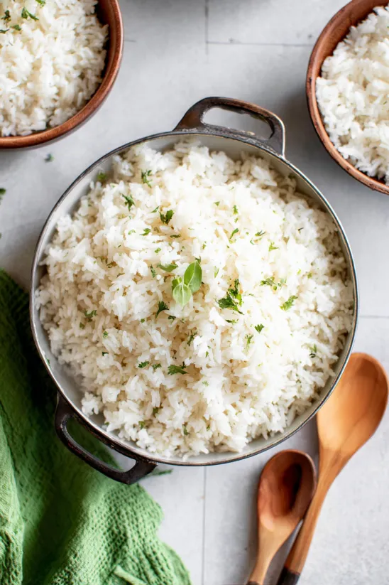 A bowl of rice with green herbs on top.