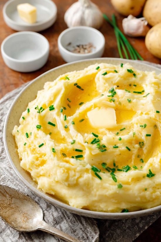 A plate of mashed potatoes with butter and herbs.