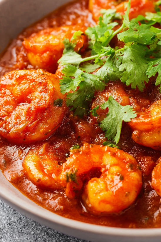 A bowl of shrimp with a green garnish.