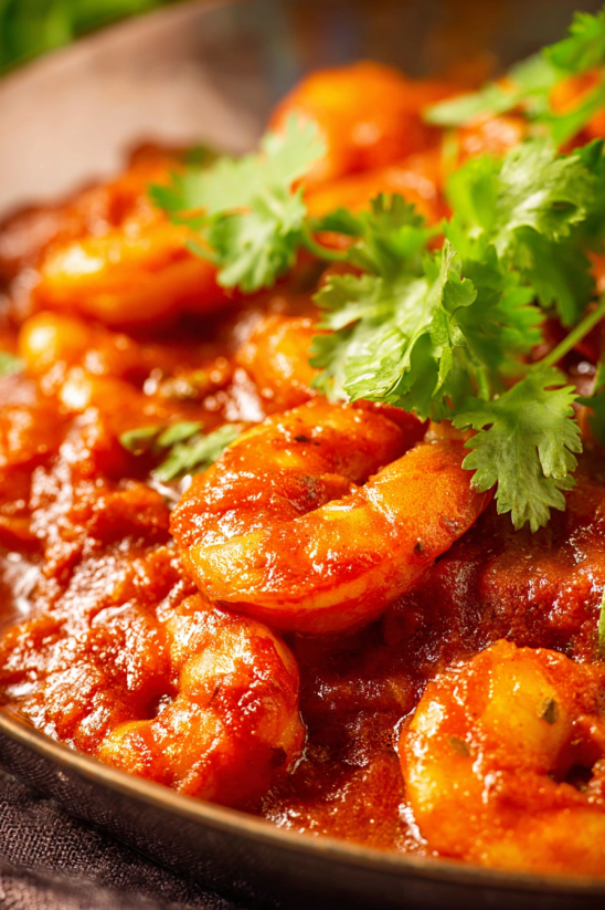 A bowl of shrimp with a green garnish.