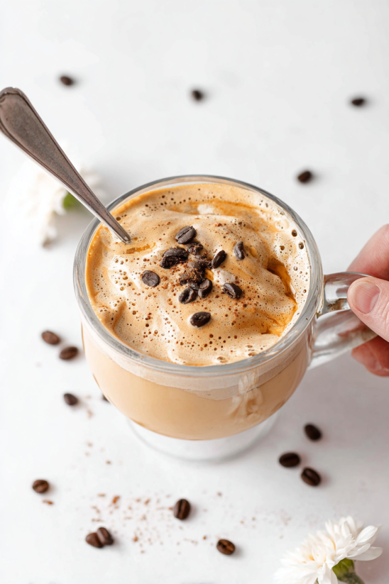A cup of coffee with chocolate chips in it.