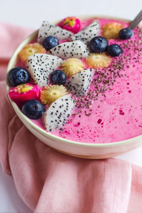 A bowl of strawberry smoothie with blueberries and coconut.