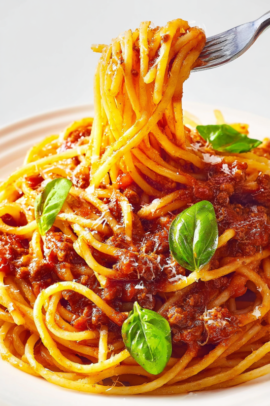 A plate of spaghetti with meat sauce and green leaves.