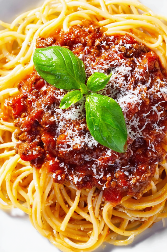A close up of a homemade bolognese sauce with a sprig of parsley on top.
