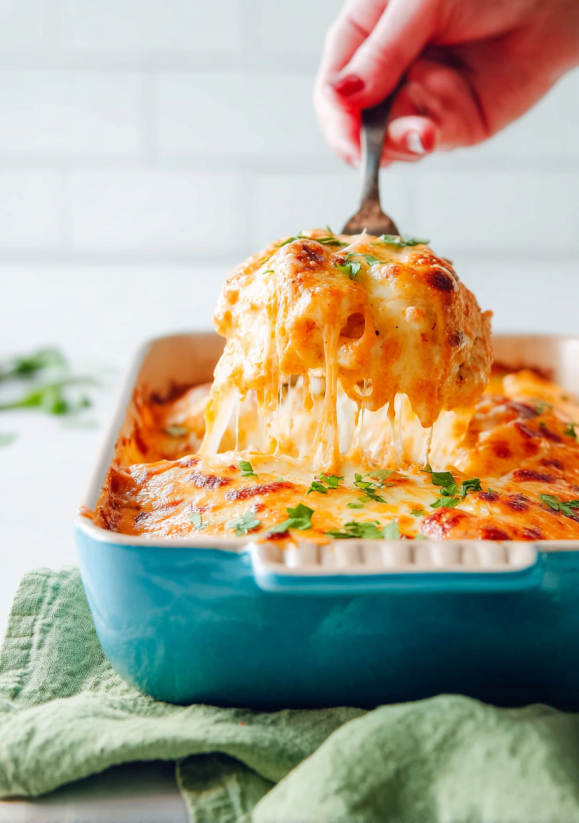 A fork is being used to cut into a cheese enchilada.