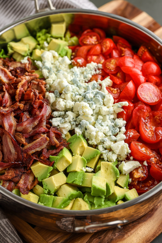 A bowl of food with bacon, tomatoes, and cheese.