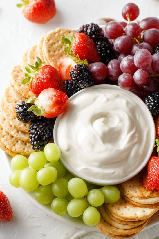 A bowl of fruit with a dollop of cream on top.