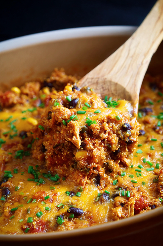 A wooden spoon is in a bowl of slow cooker chicken enchilada quinoa.