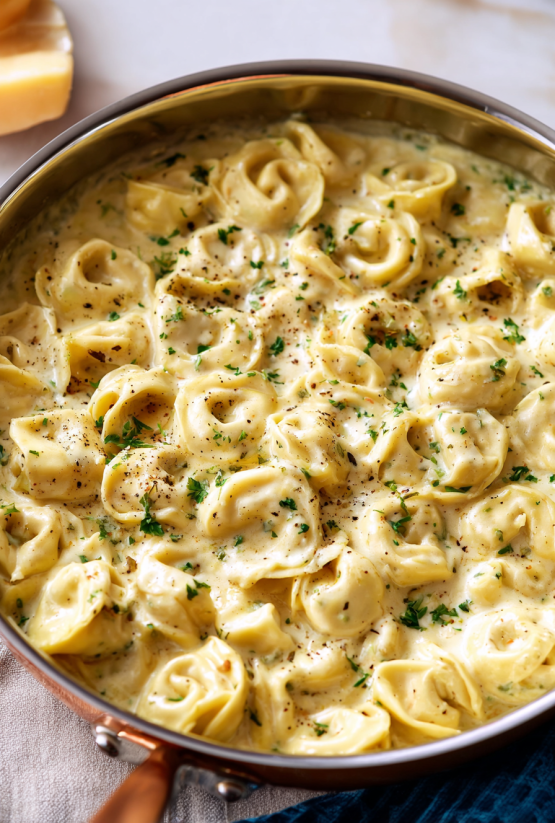 A pan of Alfredo pasta with cheese and herbs.