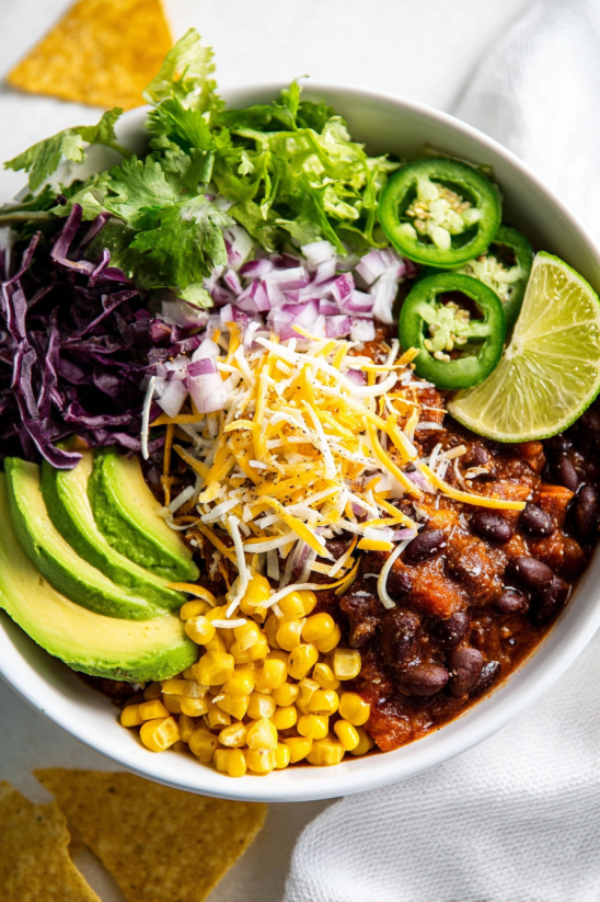 A bowl of food with a variety of ingredients including ground beef chili.