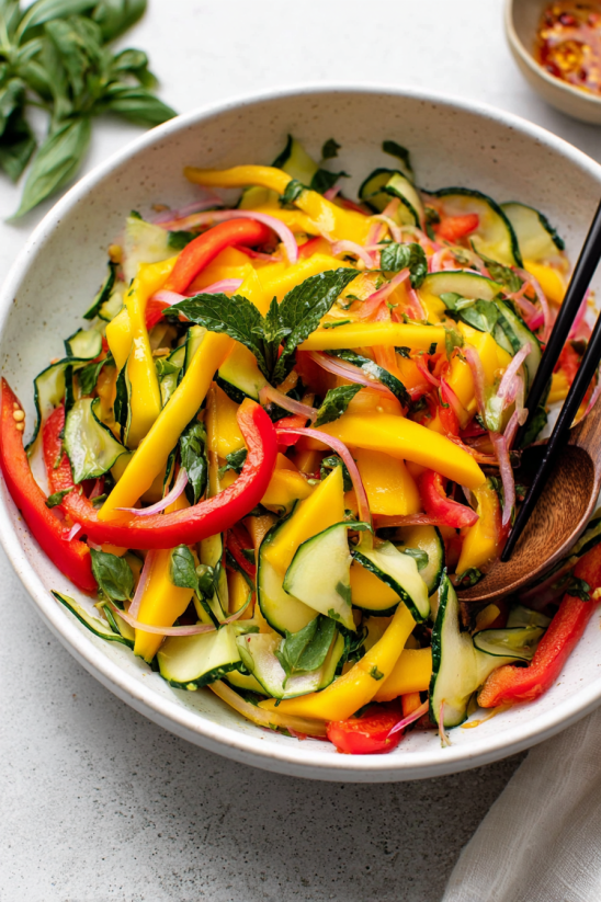 A bowl of mango salad with a spoon in it.