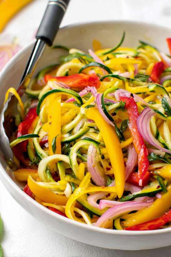A bowl of zucchini, peppers, and onions.