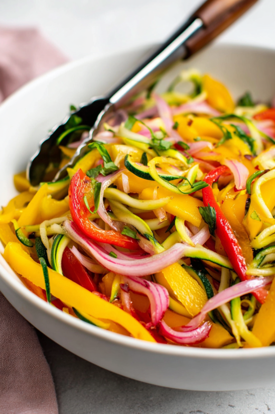A bowl of mango salad with a spoon in it.