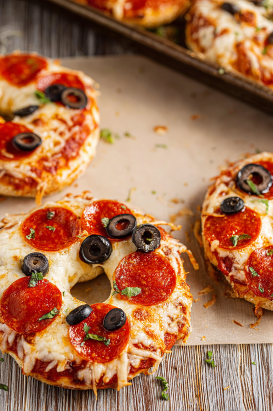 A pizza bagel with pepperoni and black olives.