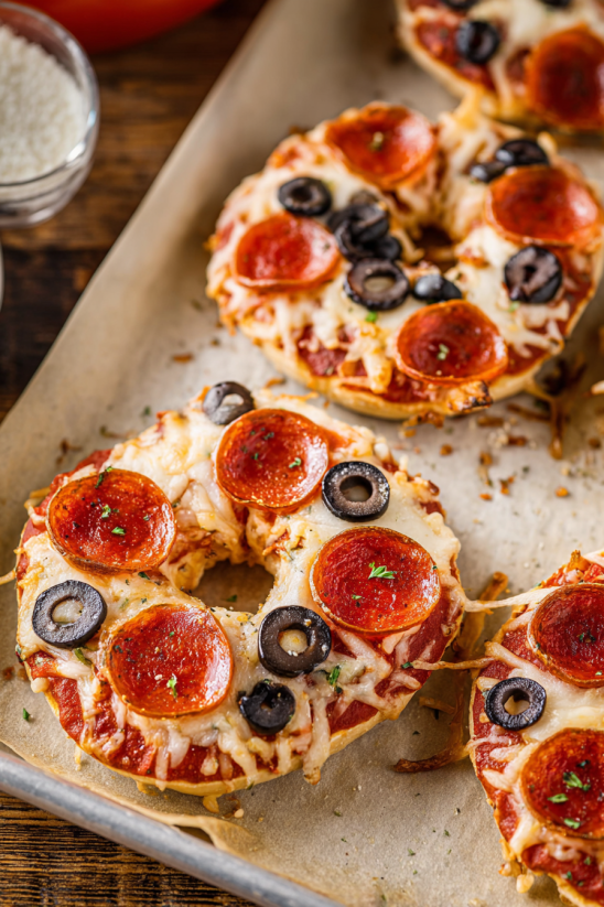 A pizza bagel with pepperoni and black olives.